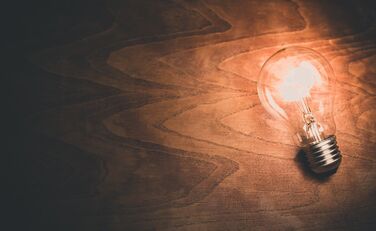 Leuchtende Glühbirne auf dunklem Holzuntergrund